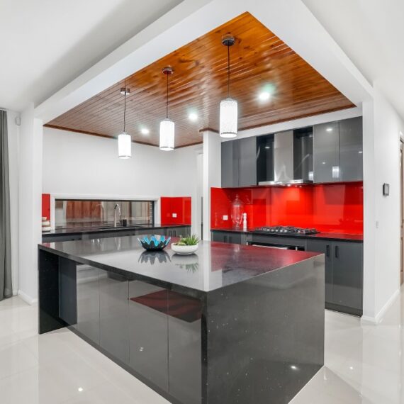 Cocina roja y negra integrada en sala de estar, abierta al salón en Toledo