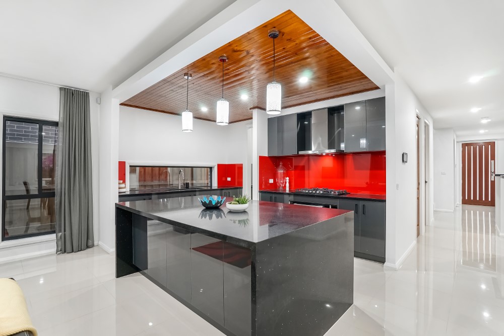 Cocina roja y negra integrada en sala de estar, abierta al salón en Toledo